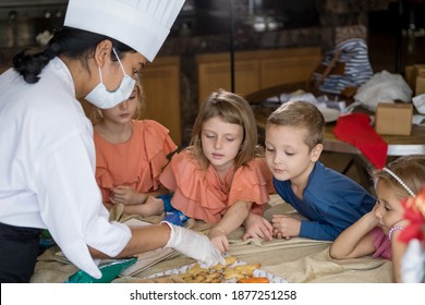 Children Decorating Christmas Biscuits And Gingerbread Cookies In Kitchen Together With Chef. Kids Cooking Class. Merry Christmas And Happy Holidays Concept