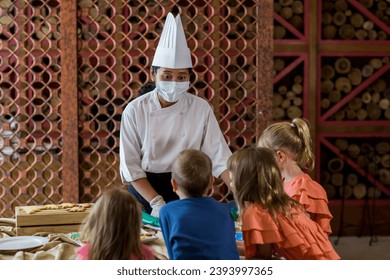 Children decorating Christmas biscuits and gingerbread cookies in kitchen together with chef. Kids cooking class. Merry Christmas and happy holidays concept - Powered by Shutterstock