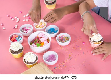 The children decorating cupcake with icing, jelly and marshmallows - Powered by Shutterstock