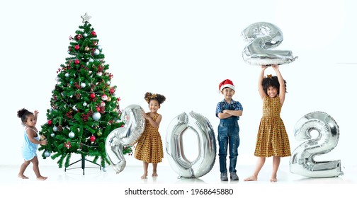 Children Of Different Color And Races Have Fun With Metallic Silver Number Balloons And Christmas Trees, A Diverse Group Of Children, Including African And Asian, 2022 Happy New Year, White Background