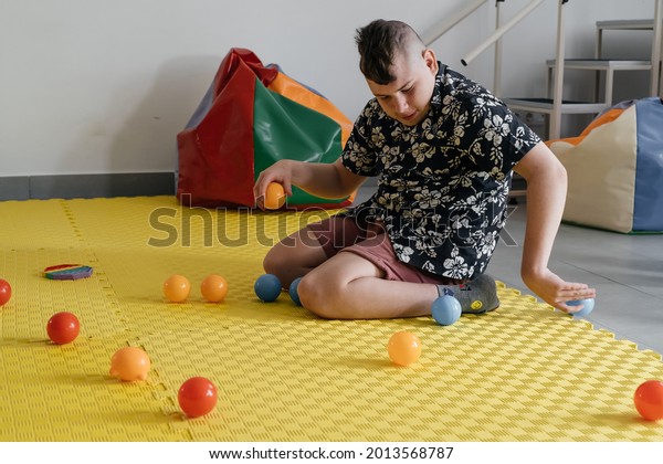 Children with disability getting sensory activity\
with toys, balls, small objects, cerebral palsy boy playing calming\
game, training fine motor skills. Rehabilitation center with\
therapist, mother