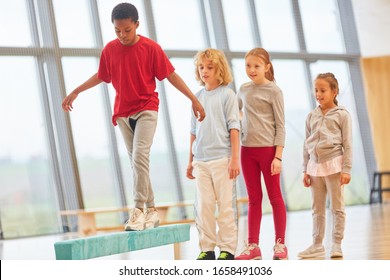 Children Do Gymnastics At The Balance Beam In Primary School Physical Education