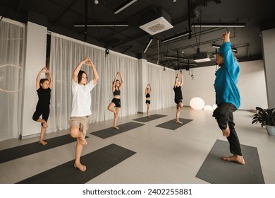 Children do yoga in the gym under the guidance of an instructor. Children's gymnastics. - Powered by Shutterstock