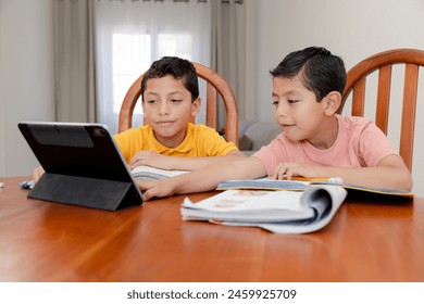 Children doing homework at home - Hispanic children learning with books and digital tablet - home schooling with technology - children learning from their iPad - Powered by Shutterstock