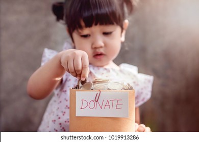 Children With Donation Concept. 2 Years Old Child Putting Money Coin Into A Donate Box