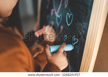 Children draw on the board with chalk.