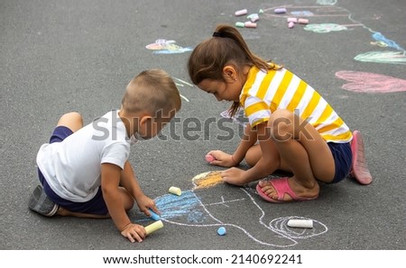 children draw on the pavement with chalk. Very good weather. selective focus