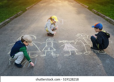 Children Is Drawing Happy Family On Asphalt In Spring Park.