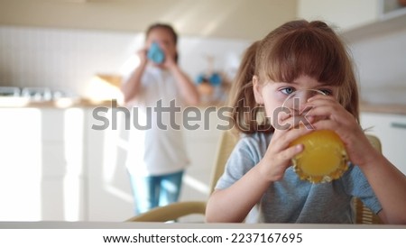 children drink juice. little girl in the kitchen drinking yellow juice from a glass cup. happy family kid dream concept. children drink juice in the kitchen lifestyle. healthy eating concept