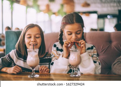 Children drink smoothie in family cafe. Two little friends celebrating birthday party in indoor restaurant. - Powered by Shutterstock