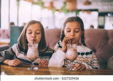 Children drink smoothie in family cafe. Two little friends celebrating birthday party in indoor restaurant. - Powered by Shutterstock