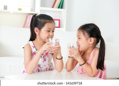 Children Drinking Milk. Asian Family At Home. Beautiful Sister Drinks Milk Together.