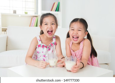 Children Drinking Milk. Asian Family At Home. Beautiful Sister Drinks Milk Together.