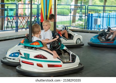 Children driving bumper car in an amusement park. Boys drive toy electric cars, funny vacations.