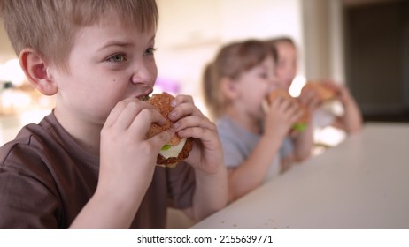 Children Eat Burgers. Fast Food Burger. A Group Of Small Children In The Kitchen Greedily Eat Fast Food Burgers. Big Family Small Fun Kids Having Breakfast In The Morning In The Kitchen Eating Burger