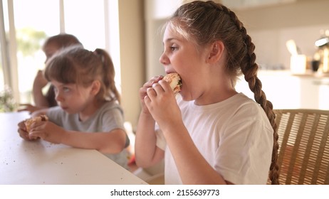 Children Eat Burgers. Fast Food Burger. A Group Of Small Children In The Kitchen Greedily Eat Fast Food Burgers. Big Family Small Kids Having Sun Breakfast In The Morning In The Kitchen Eating Burger