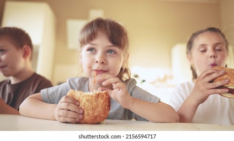 Children Eat Burgers. Fast Food Burger. A Group Of Small Children In Fun The Kitchen Greedily Eat Fast Food Burgers. Big Family Small Kids Having Breakfast In The Morning In The Kitchen Eating Burger