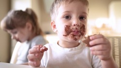 Children Eat Chocolate. Dirty Little Baby Kids Lifestyle In The Kitchen Eating Chocolate In The Morning. Happy Family Eating Sweets Kid Dream Concept. Baby Dirty Face Eating Chocolate Cocoa
