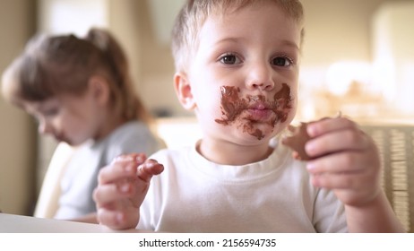 children eat chocolate. dirty little baby kids lifestyle in the kitchen eating chocolate in the morning. happy family eating sweets kid dream concept. baby dirty face eating chocolate cocoa - Powered by Shutterstock