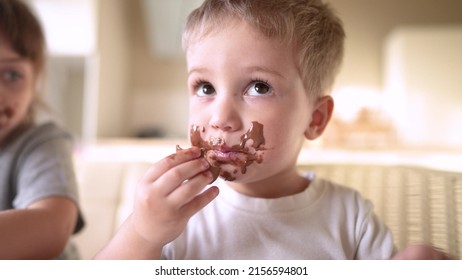 children eat chocolate. dirty little baby kids in the kitchen eating chocolate in the morning. happy family lifestyle eating sweets kid dream concept. baby dirty face eating chocolate cocoa