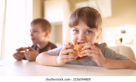 Children Eat Fun Burgers. Fast Food Burger. A Group Of Small Children In The Kitchen Greedily Eat Fast Food Burgers. Big Family Small Kids Having Breakfast In The Morning In The Kitchen Eating Burger