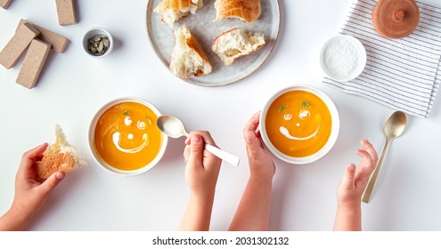 Children eat pumpkin cream soup and cartoon smiles from cream  no face
