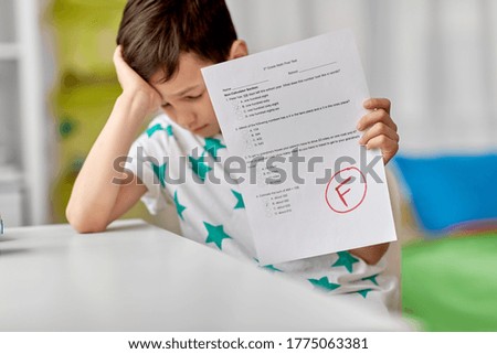 children, education and learning concept - sad student boy with failed school test at home