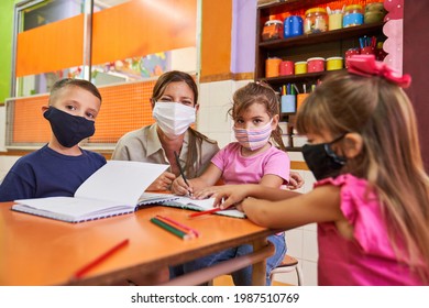 Children And Educator In A Daycare Center While Studying With Face Masks Because Of Covid-19 And Coronavirus