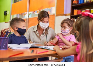 Children And Educator In Daycare With Face Mask Because Of Covid-19 And Coronavirus