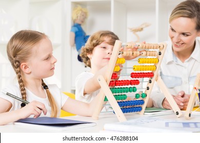 Children in elementary school learning to count on a colourful abacus with the help of their teacher - Powered by Shutterstock