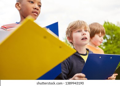 Children As Elementary School Students Explore Nature In A Scavenger Hunt