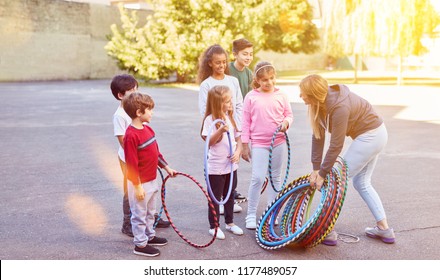 Children In Elementary School Together Do Sports On School Playground With Tires And Sports Teacher