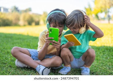 Children Enjoying Music and Games on Smartphones. Happy children with headphones and smartphones in the park. - Powered by Shutterstock