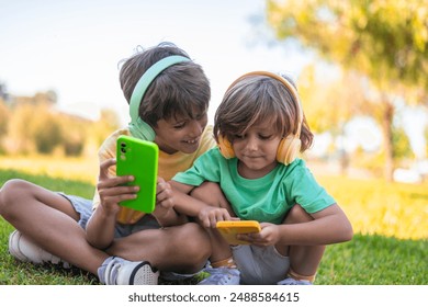 Children Enjoying Music and Games on Smartphones. Happy children with headphones and smartphones in the park. - Powered by Shutterstock