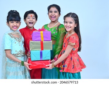 Children in ethnic clothing holding plenty of gifts in hand , looking at the camera and smiling