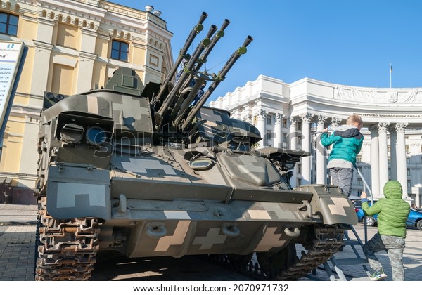 Children\
examine a military anti-aircraft tank of the Ukrainian army.\
Exhibition of military equipment in Kiev. Modern military\
technology. Ukraine. Kiev. October 15,\
2021