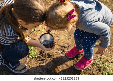 Children examine the soil with a magnifying glass. Selective focus. Kid. - Powered by Shutterstock