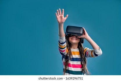 Children experiencing virtual reality isolated on blue background. Surprised cute girl looking in VR glasses.