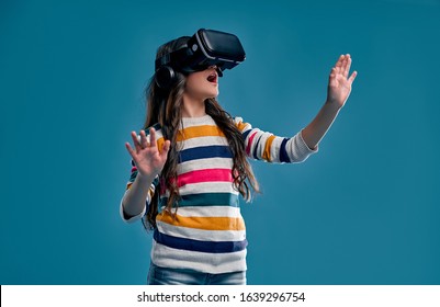 Children experiencing virtual reality isolated on blue background. Surprised cute girl looking in VR glasses. - Powered by Shutterstock