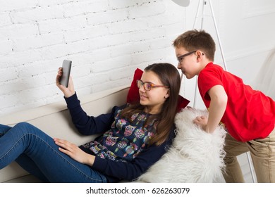 Children In Eye Glasses Look Into Tablet. Computer Games, Social Networks And Media Addiction Concept. Girl And Boy With Tablet. Eyesight, Eyewear For Kids.