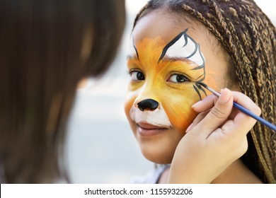Children face painting. Artist painting little african-american girl like tiger, copy space
