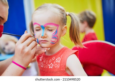 Children face painting. Artist painting little preschooler girl like butterfly. Creative activities for kids