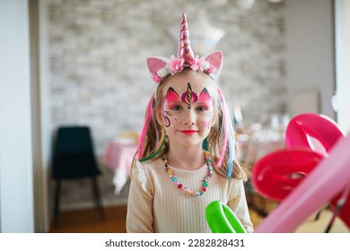 Children face painting. Little preschooler girl in unicorn costume with facepaint on a birthday party. Creative activities for kids - Powered by Shutterstock