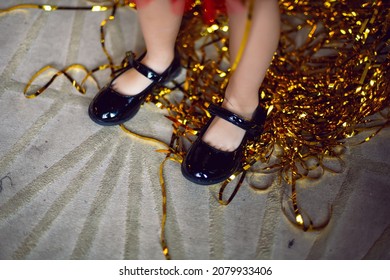 children feet with black shoes and golden rain on the carpet at Christmas - Powered by Shutterstock