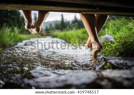 Children feet playing and having fun time on the beautiful mountain creek