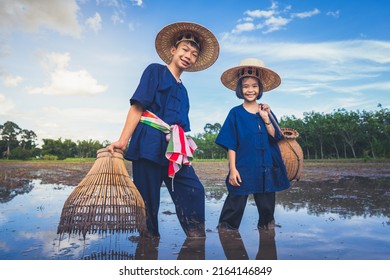 Children Finding Fish On Tradition Tool For Catch Fish In Rice Field Of Rural, Asian Kid Catching Fish In Mud On Beautiful Landscape Sky And Field Background, Happy People Of Activity, Fishing Concept