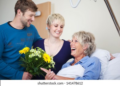 Children with flower bouquet visiting happy mother in hospital