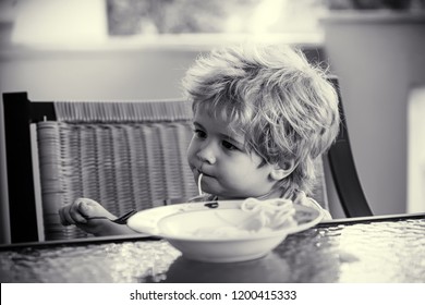 Children Food. Adorable Kid With One Spagetti In His Mouth Is Being Distracted From Eating Lunch. Naughty Boy Don't Want To Eat Anymore. Eating. Spaghetti At Dinner. Cute Boy Holding A Fork