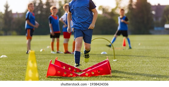 Children football player with training hurdles. Soccer agility training equipment. Kids playing sports on grass field. Happy boys practice sports. Kids football speed training - Powered by Shutterstock