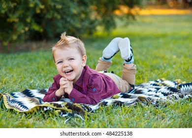 Children Genuine Emotions. Happy Baby Lying On Green Grass And Smiling